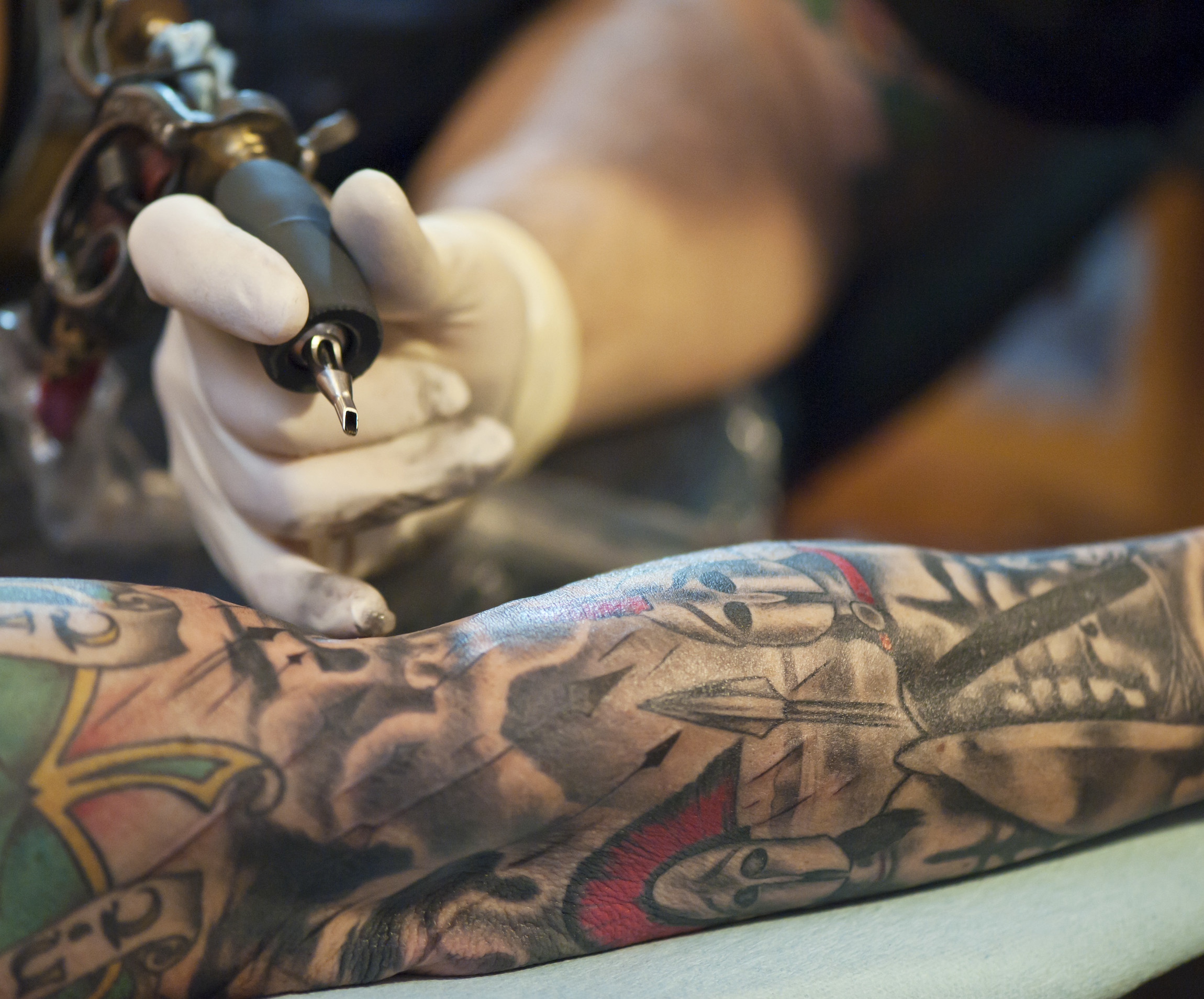 A tattoo artist working on someone's arm
