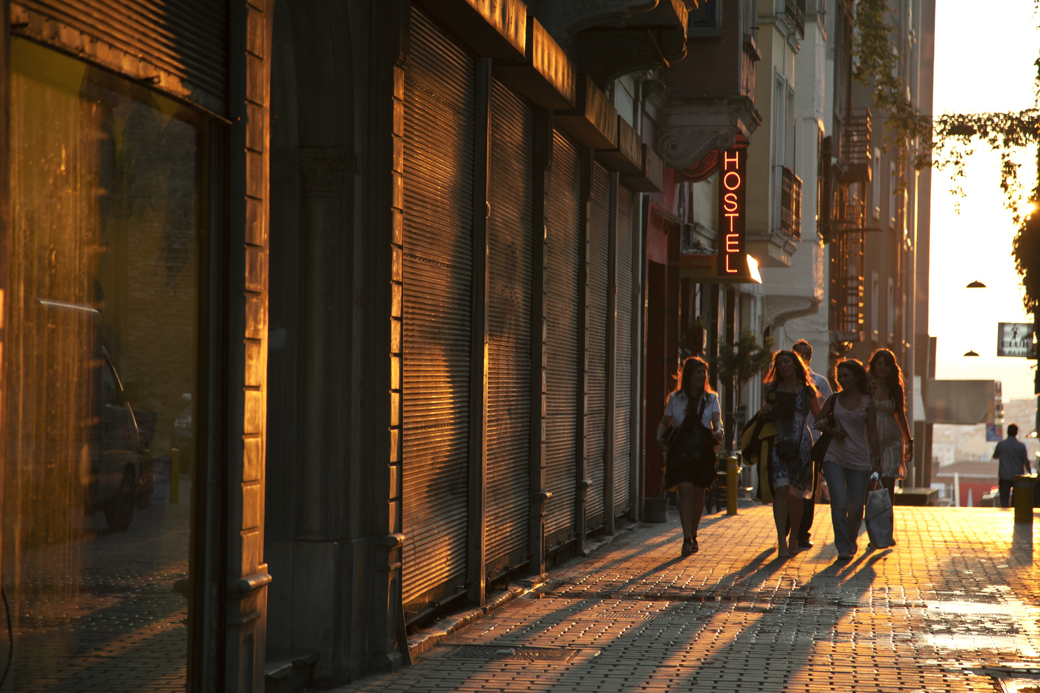 Group of women walk past a hostel at sunset.