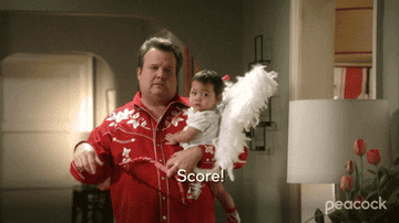 gif of cam from modern family holding baby lily, making a &quot;cha-ching&quot; motion, and saying &quot;score&quot;