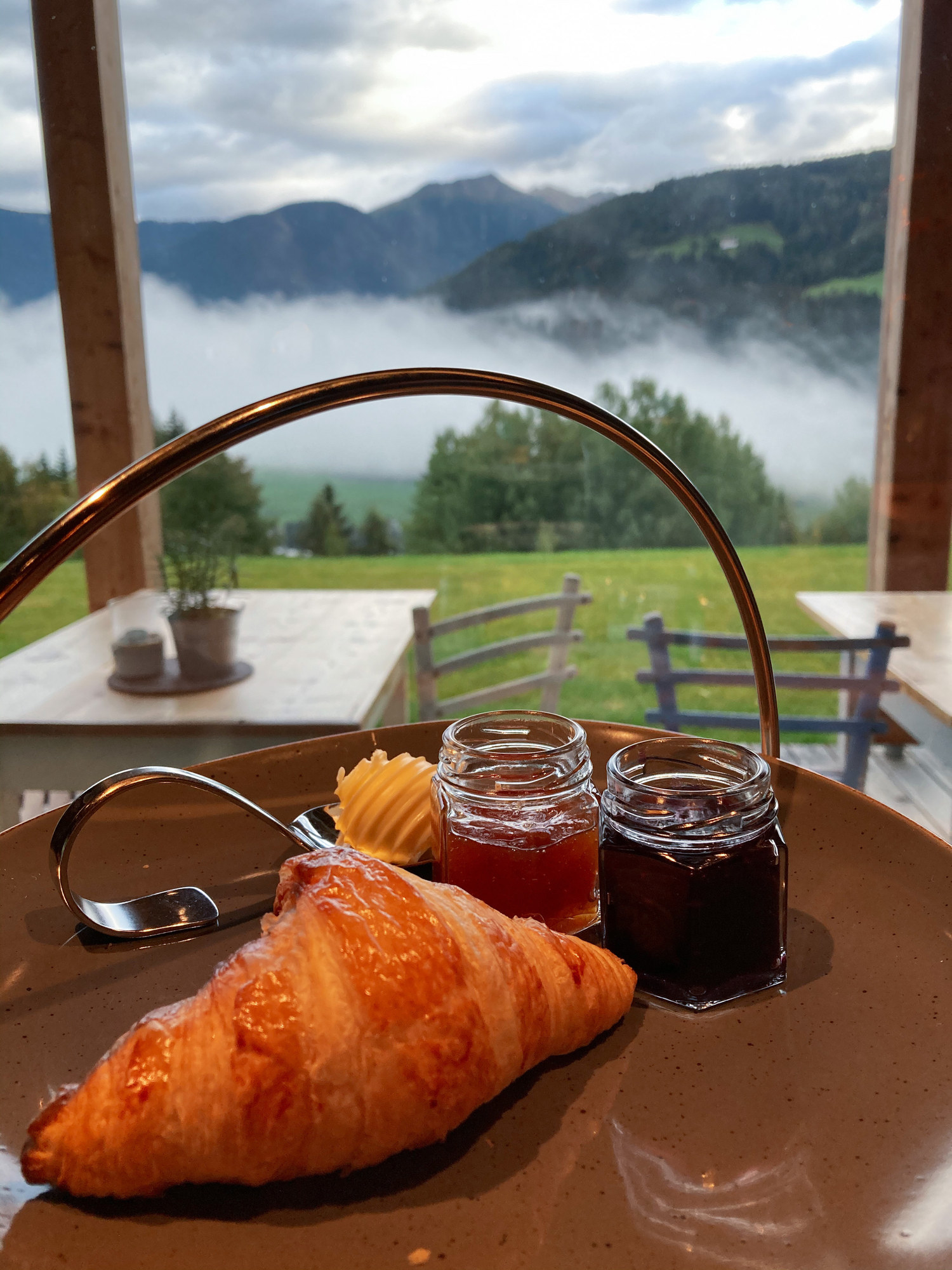 Croissants, butter, and jam on a table with a view of mountains