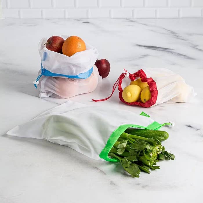 three bags that have greens, lemons and apples and oranges in them