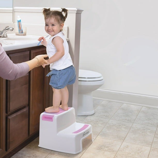 The step stool in white with pink steps and a child on it