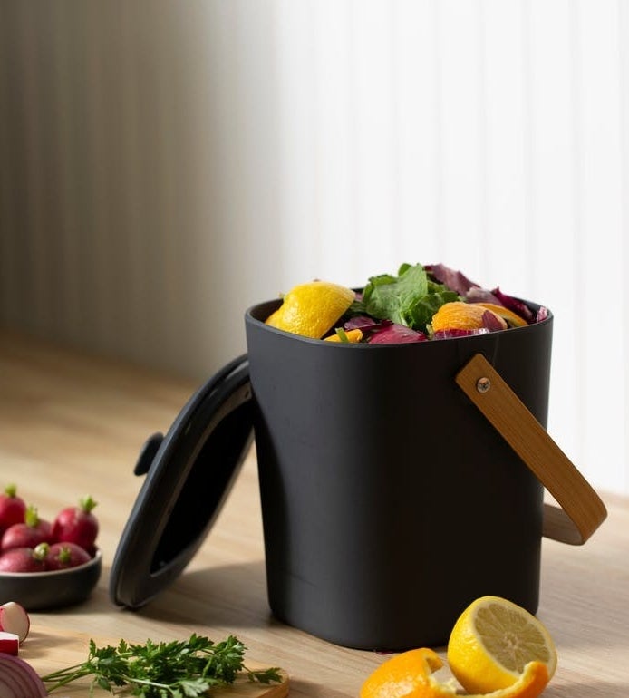 dark grey compost bin with a lid and a wood handle