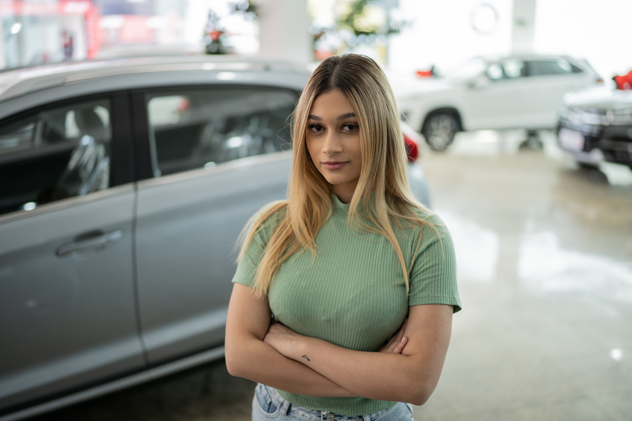 A young girl standing in a car showroom