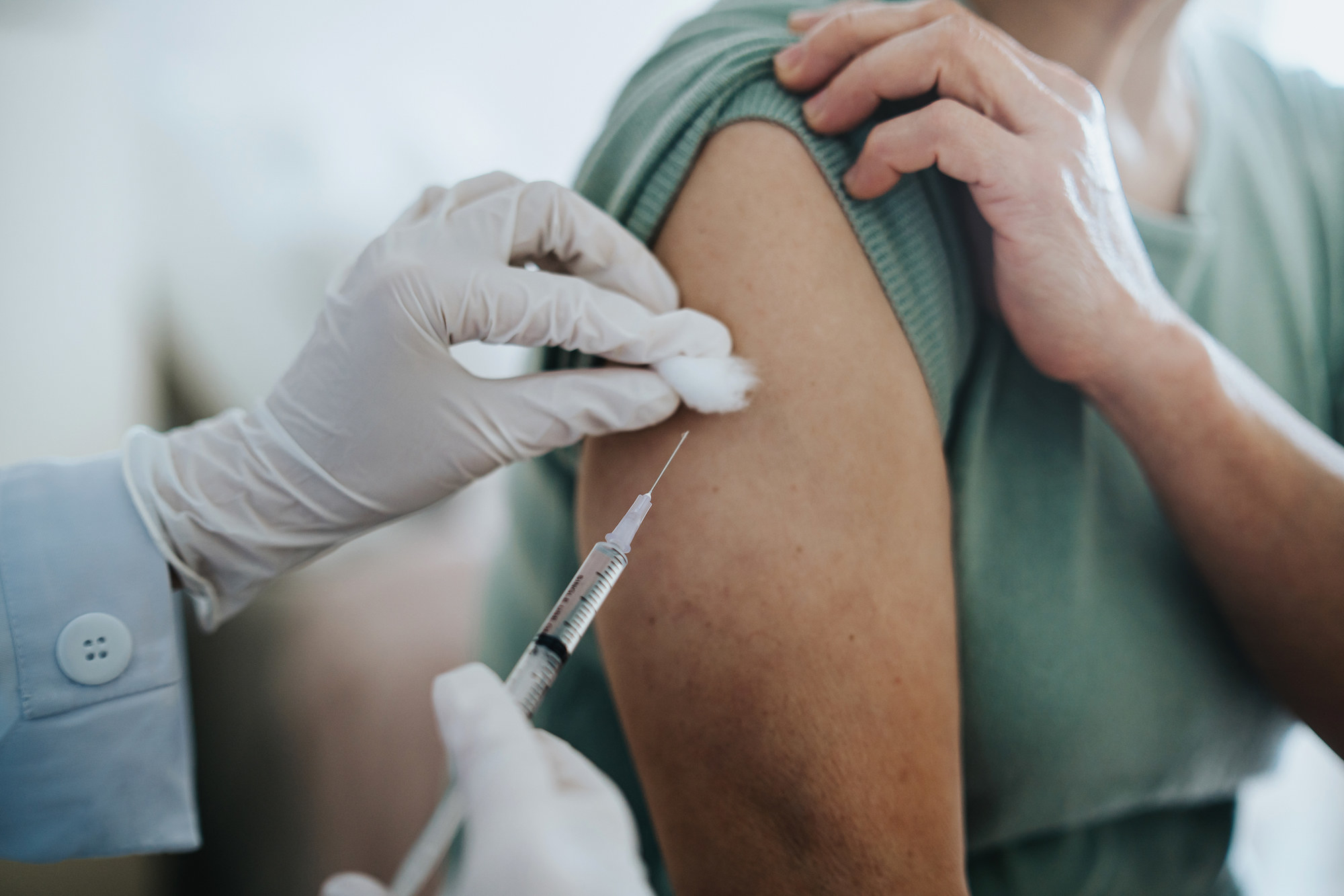 A doctor administrating a vaccine into a person&#x27;s arm