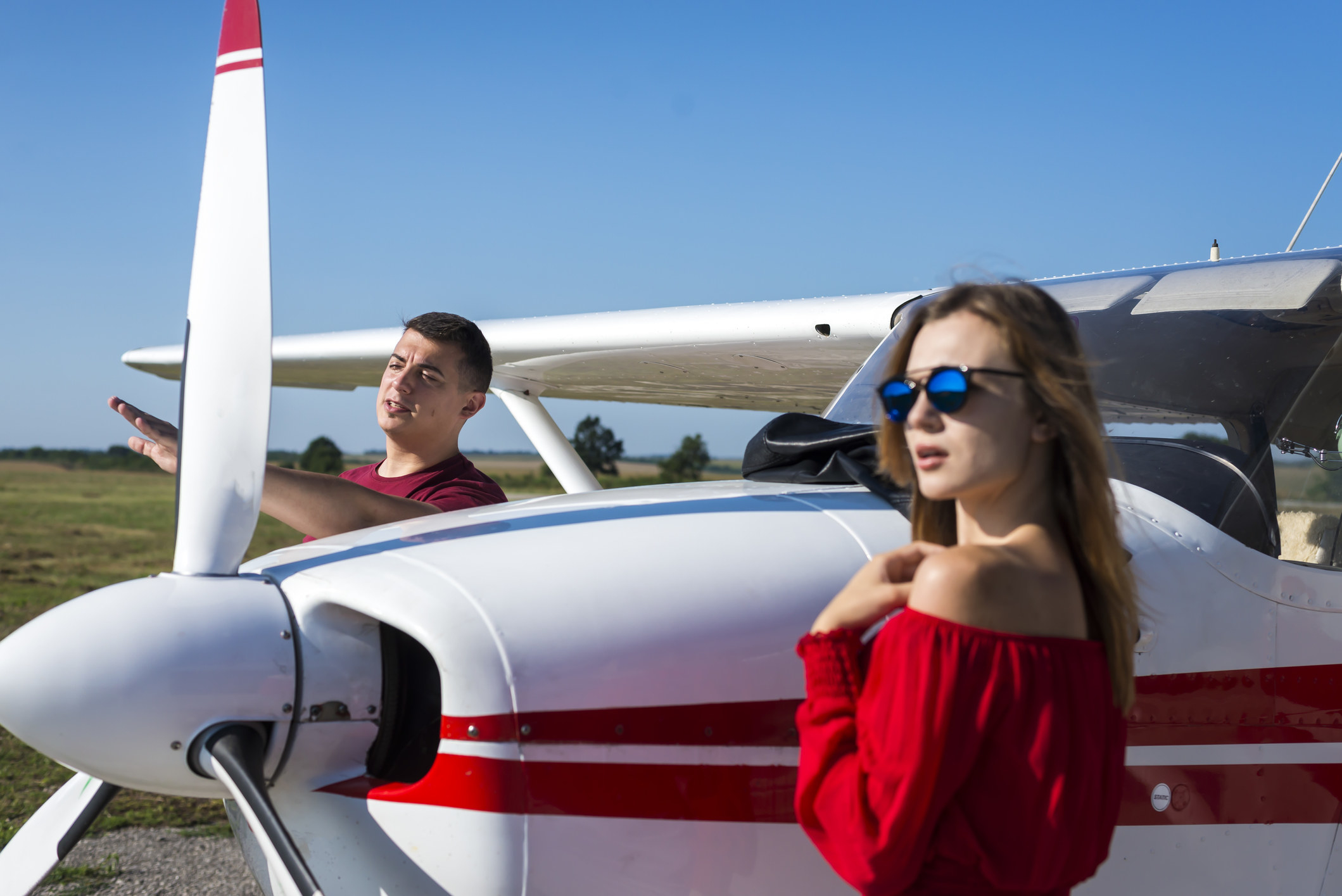 Two young people standing next to a small plane