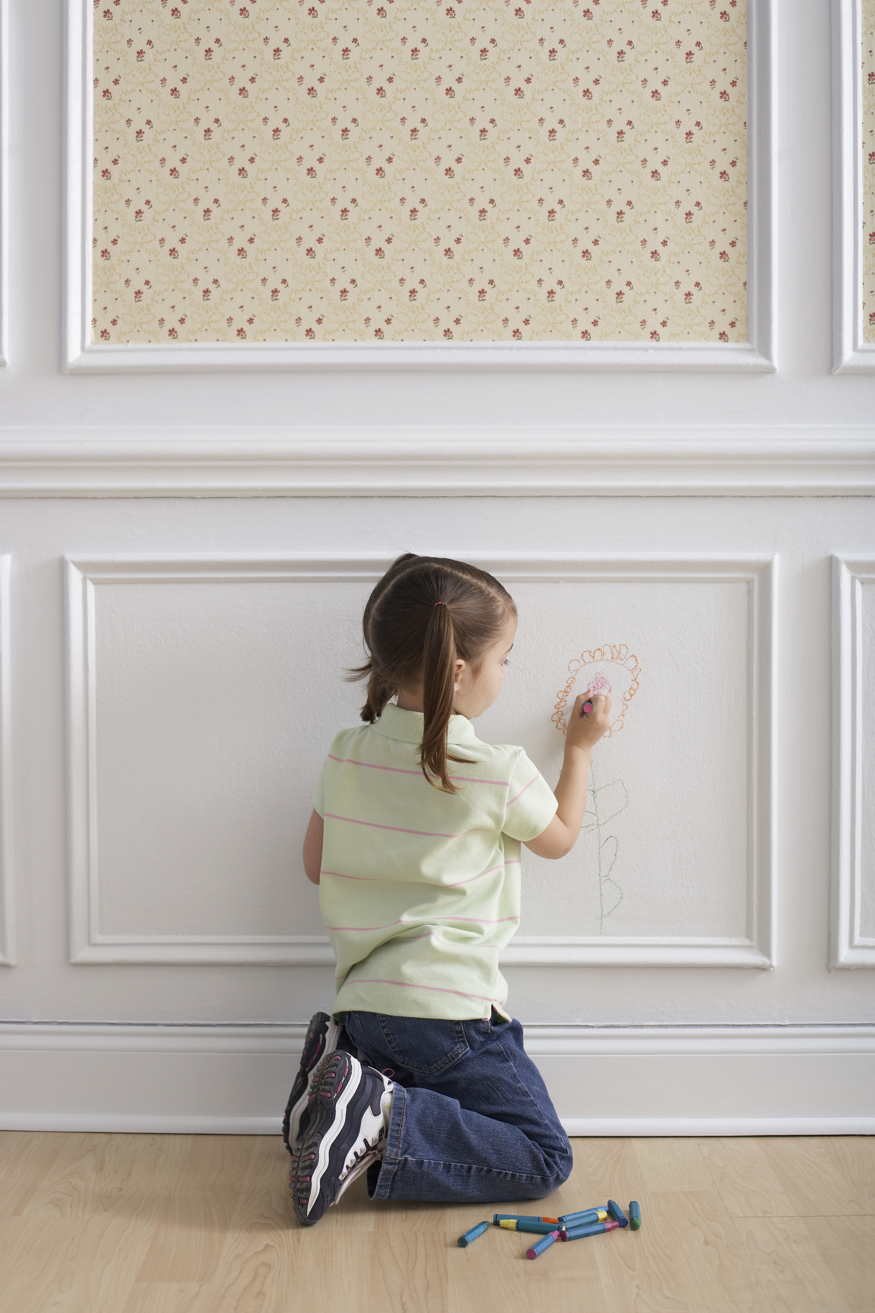 kid drawing with crayons on the wall