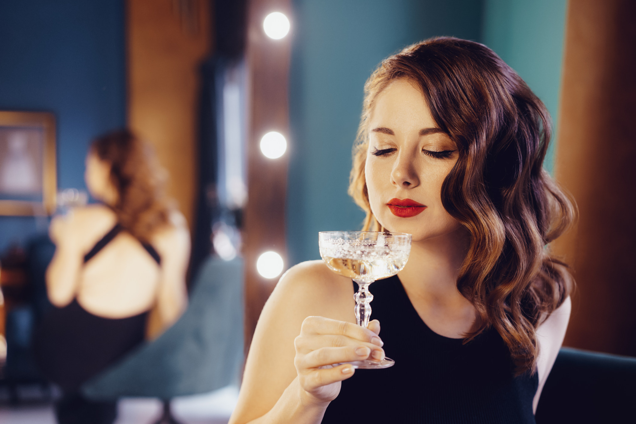 A young woman sipping champagne from a glass