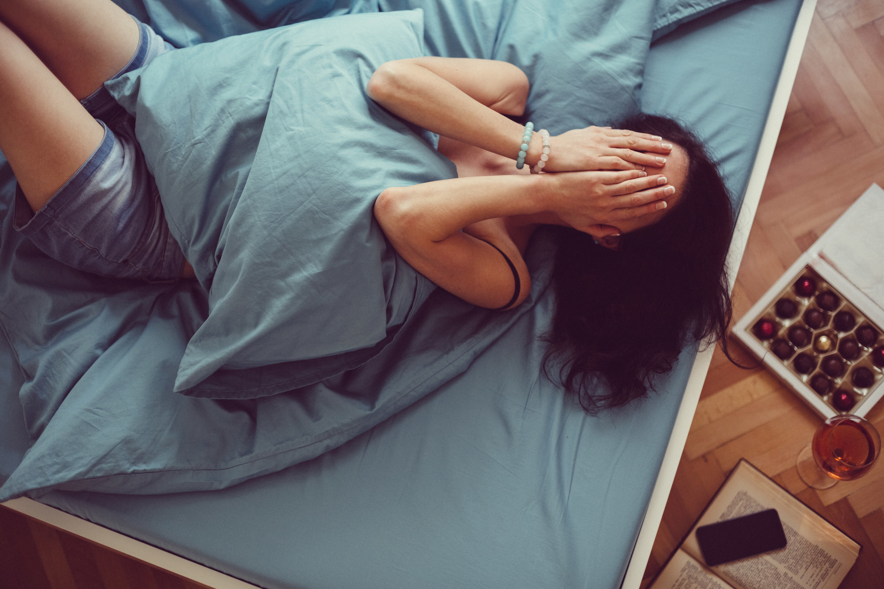 woman laying in bed covering face