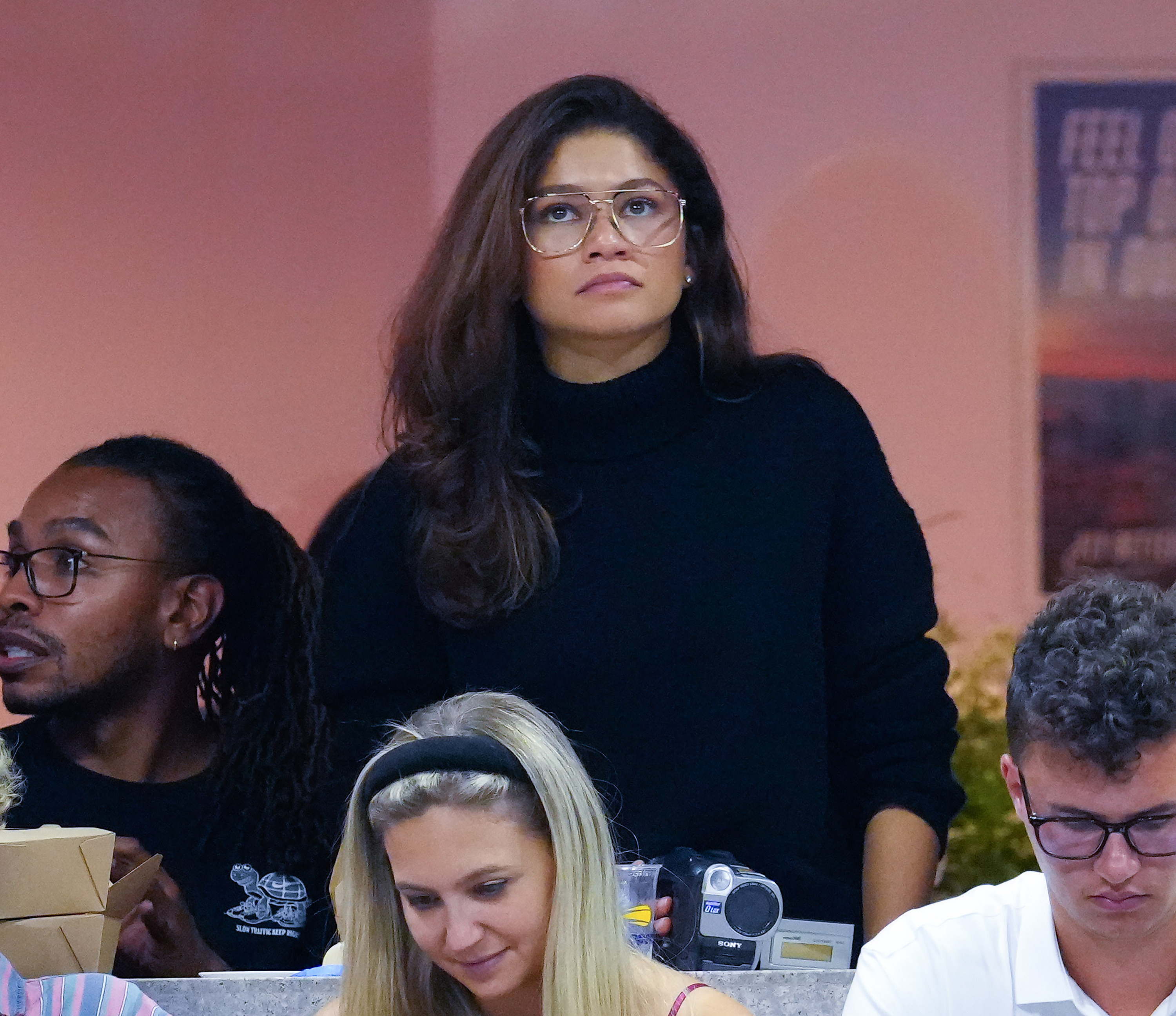 she's looking up at something dressed in a sweater for an event
