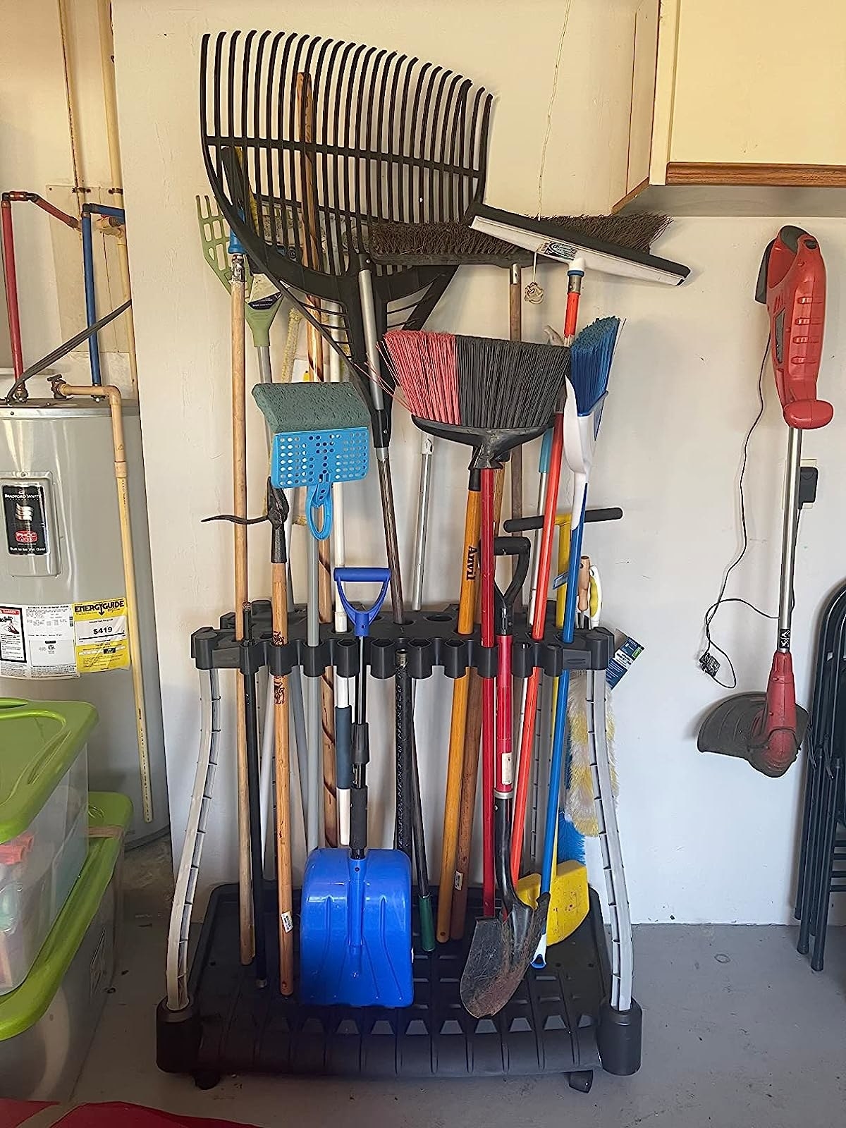 Reviewer&#x27;s photo of the yard tool organizer full of rakes, shovels, and other tools