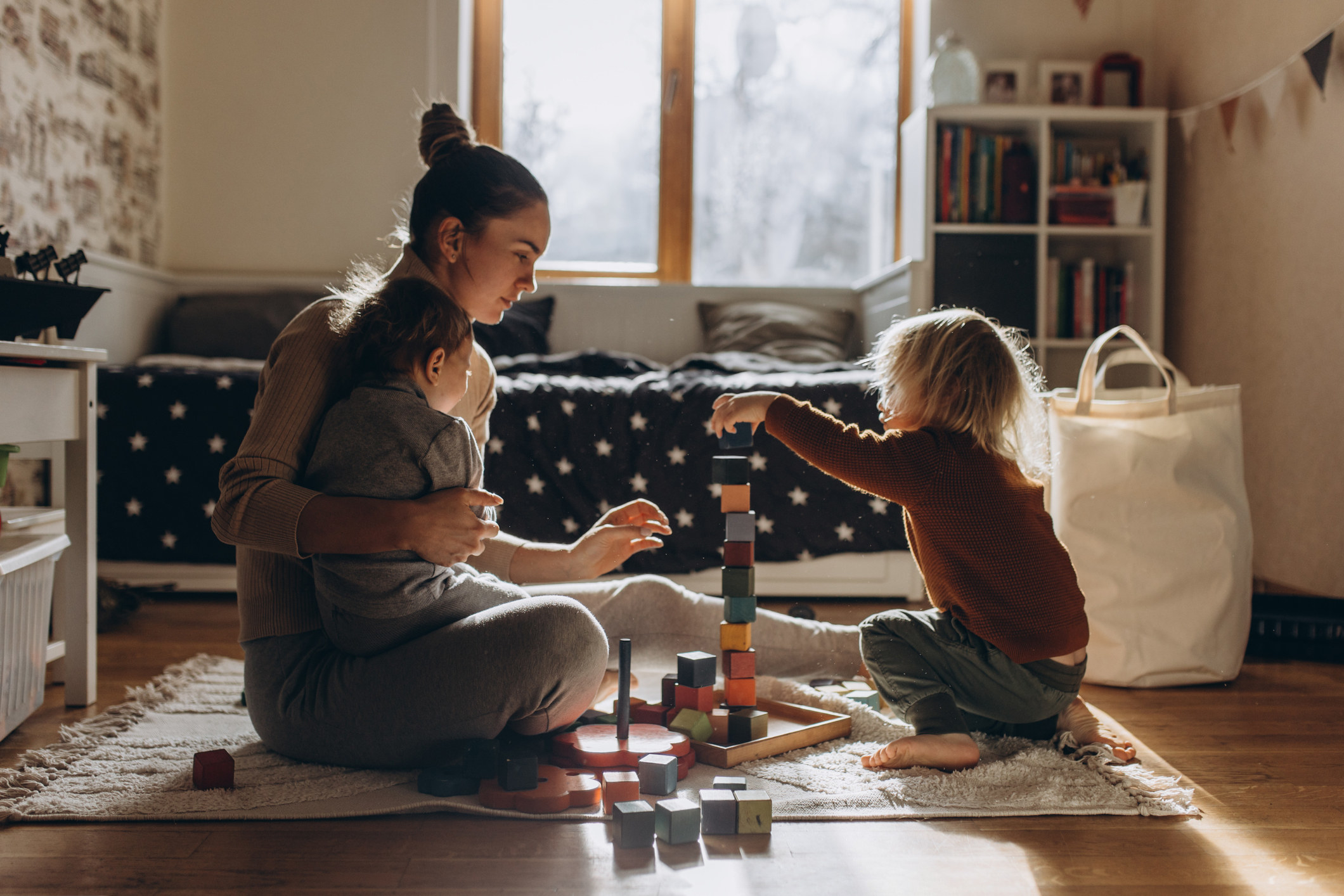 A parent and two children play with building blocks