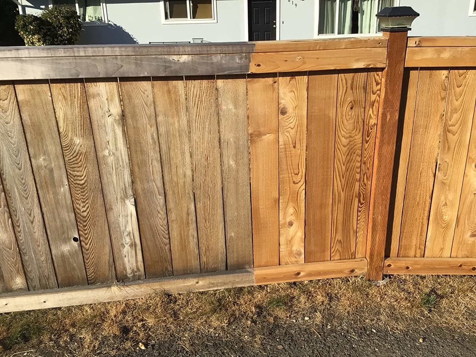 Reviewer&#x27;s photo of their fence showing one side before using the power washer and the other side after using the power washer