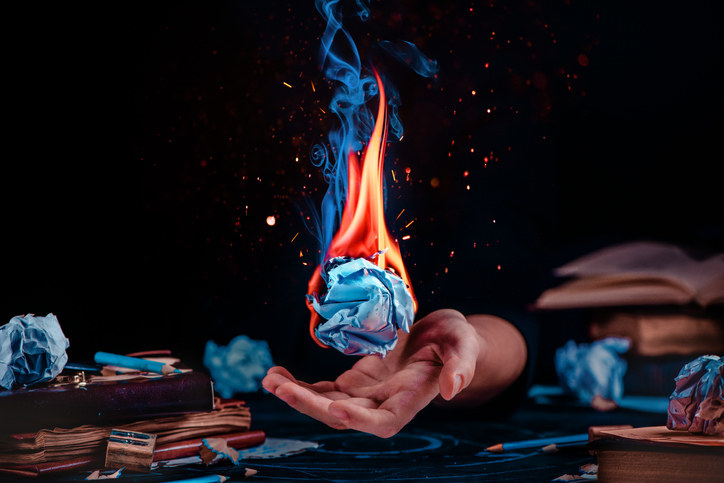 A hand reaching out for a paper on fire
