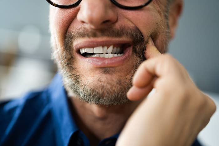 A man with a toothache rubbing his cheek
