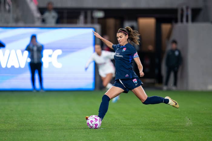 Alex Morgan kicks a soccer ball on a field