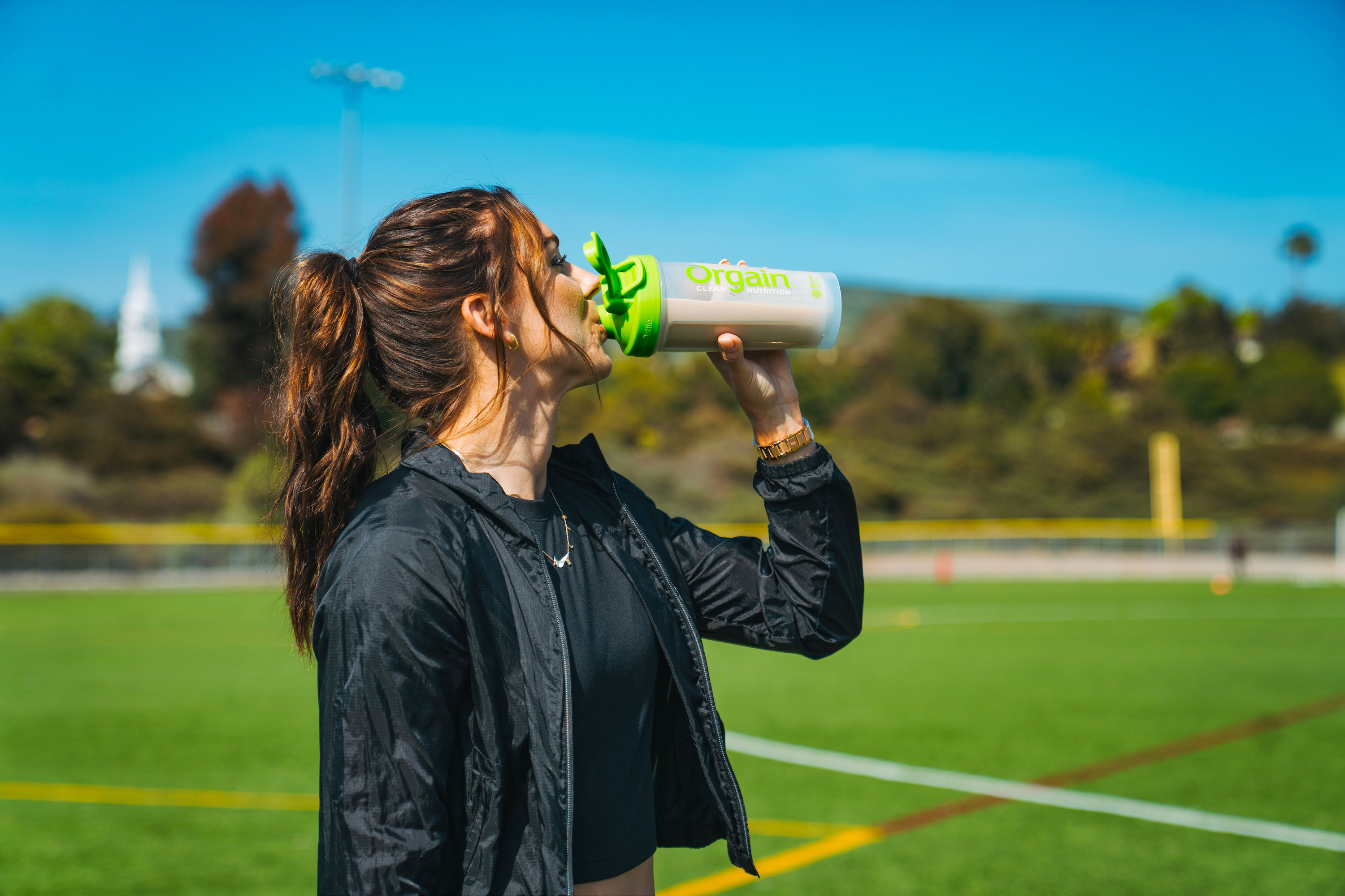 Alex Morgan drinks from a protein shaker bottle