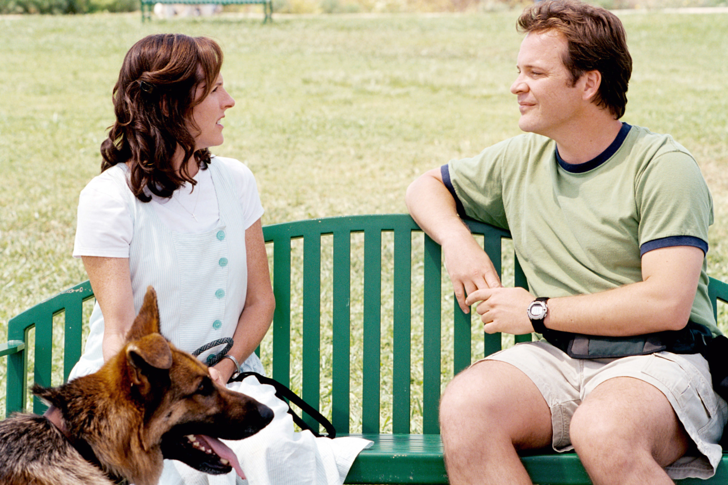 A woman with a dog sits with a man at a bench
