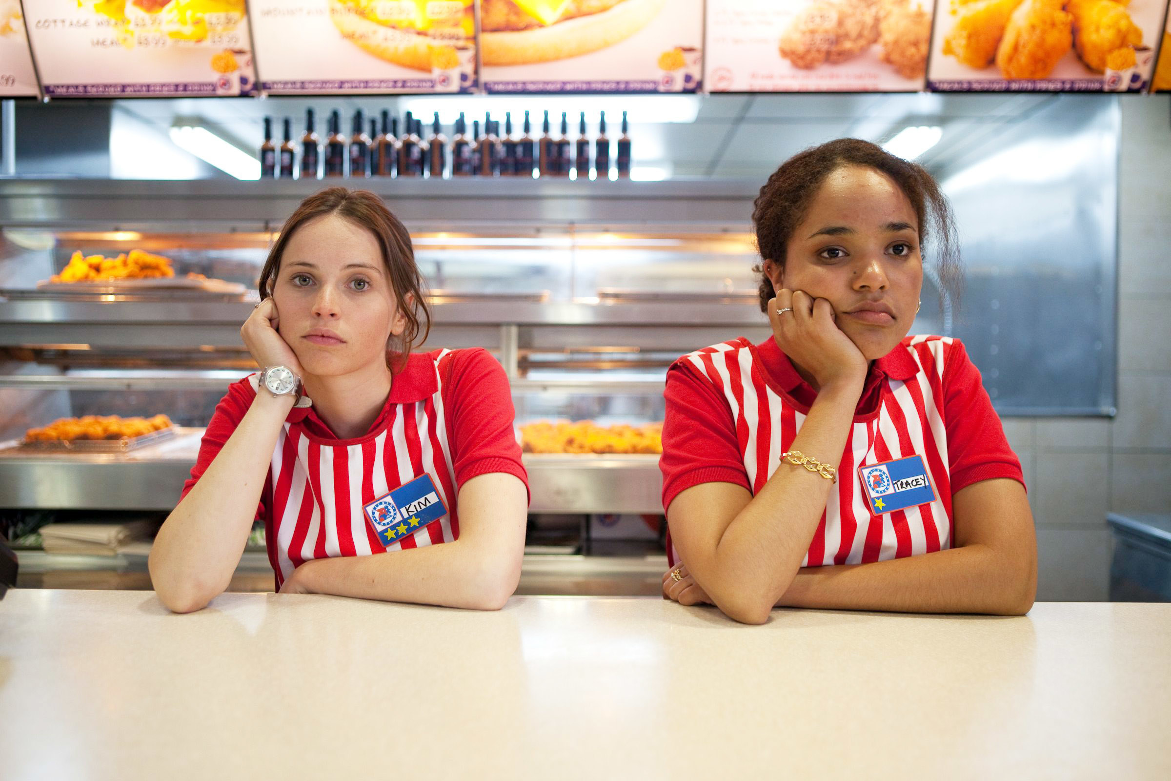 Two fast-food workers behind a counter looking glum