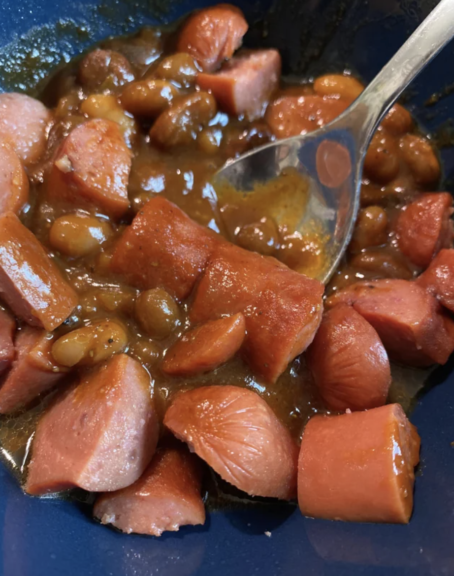 Sliced hot dogs in baked beans.