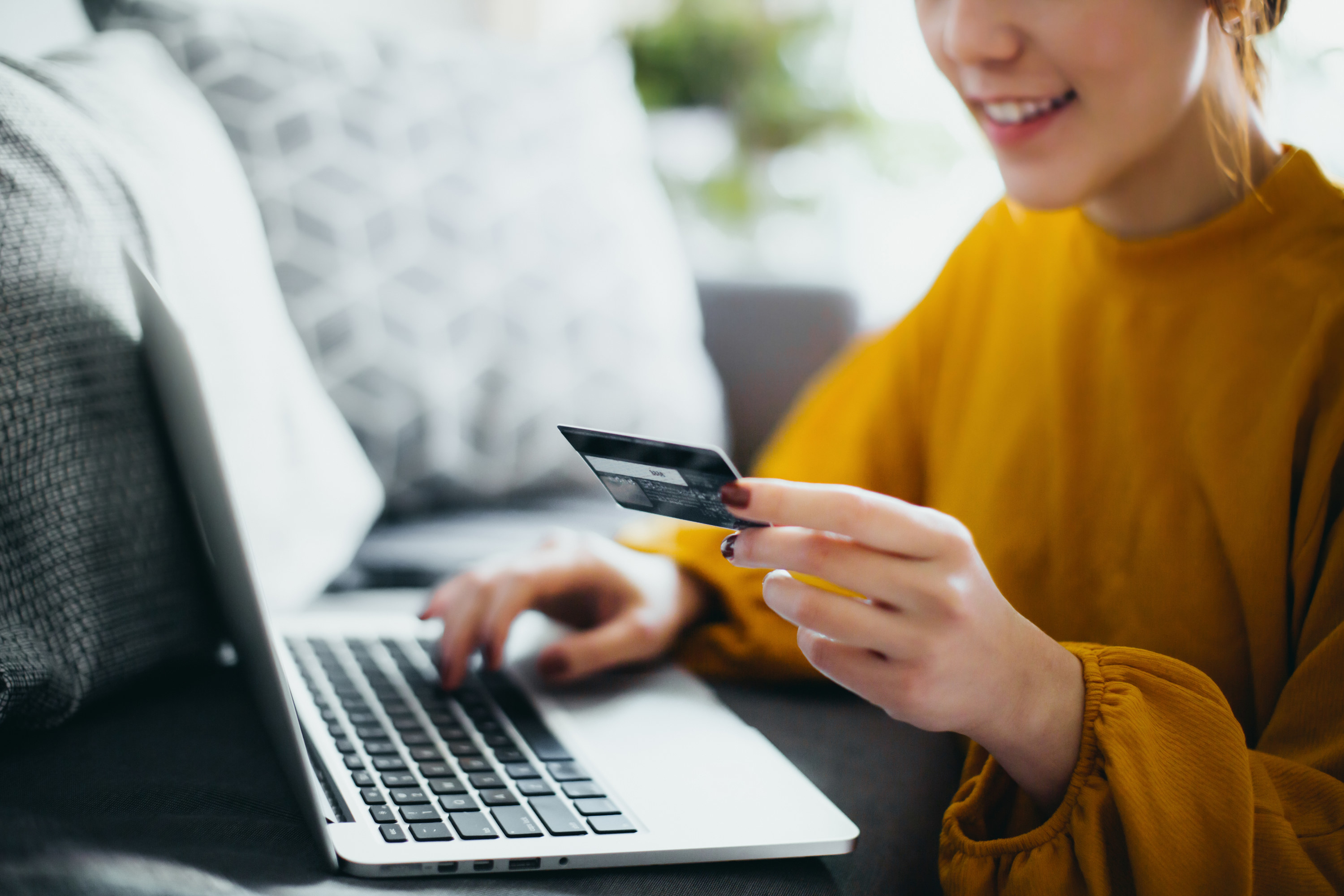 A woman holding a credit card and typing on a laptop