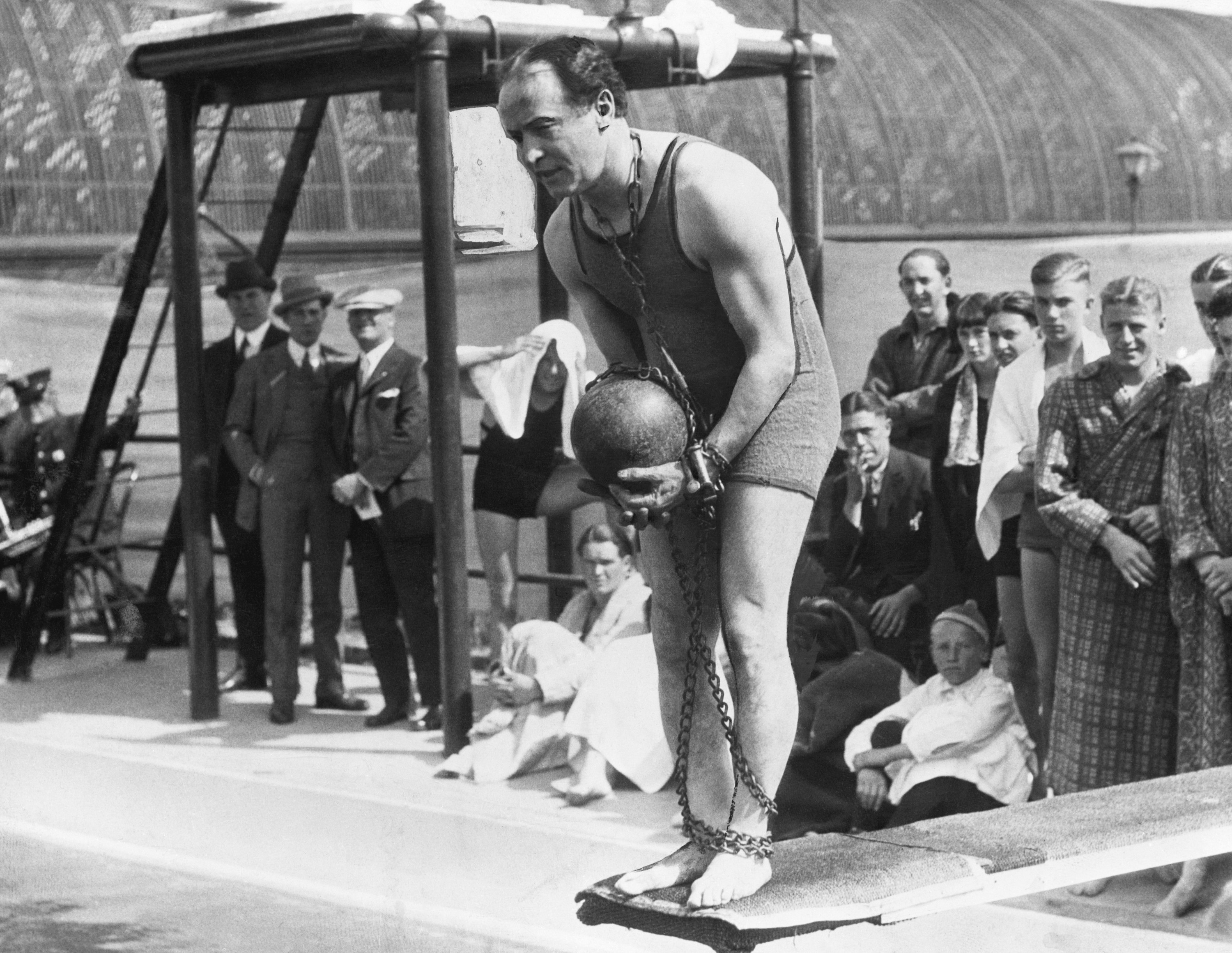 Harry Houdini on diving board with ball and chain about to perform a stunt