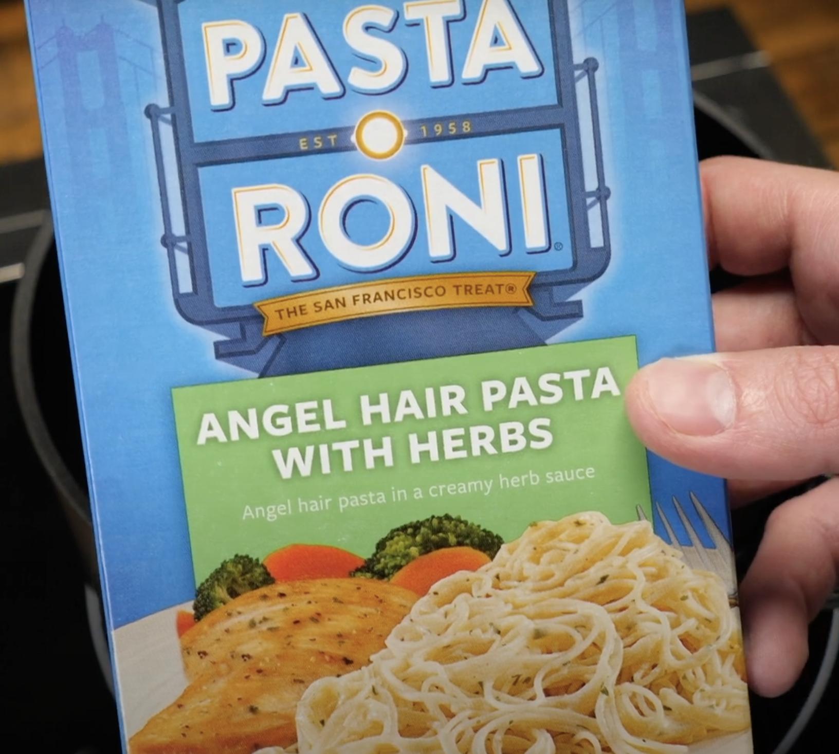 A hand holding Pasta Roni box.