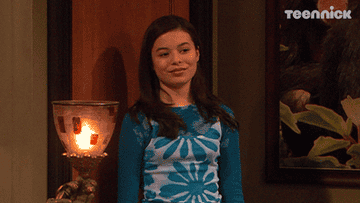 Gif of Miranda Cosgrove in &quot;Drake &amp;amp; Josh&quot; leaning against a door with a smug smile on her face