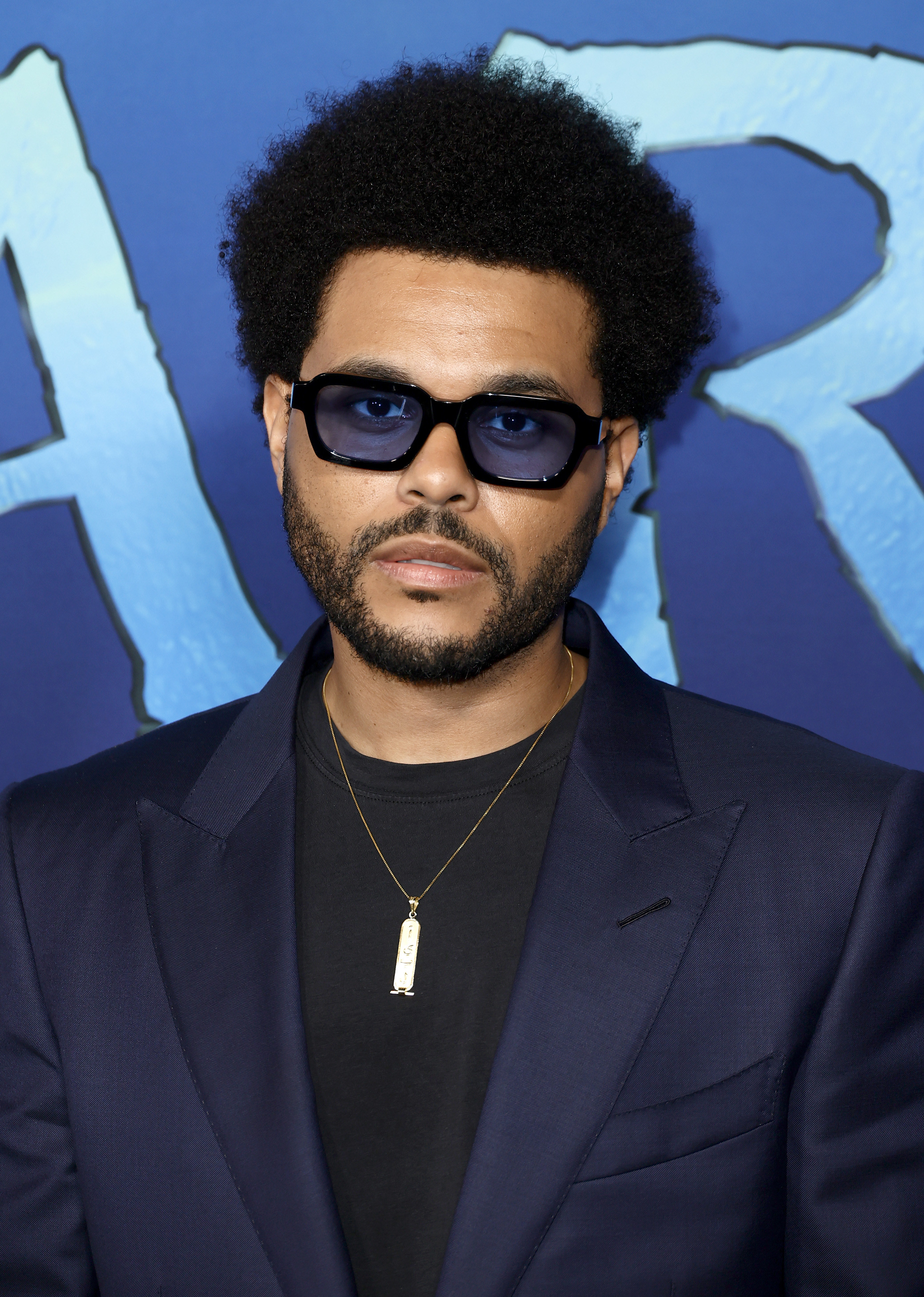 Close-up of Abel in a suit jacket and wearing a necklace