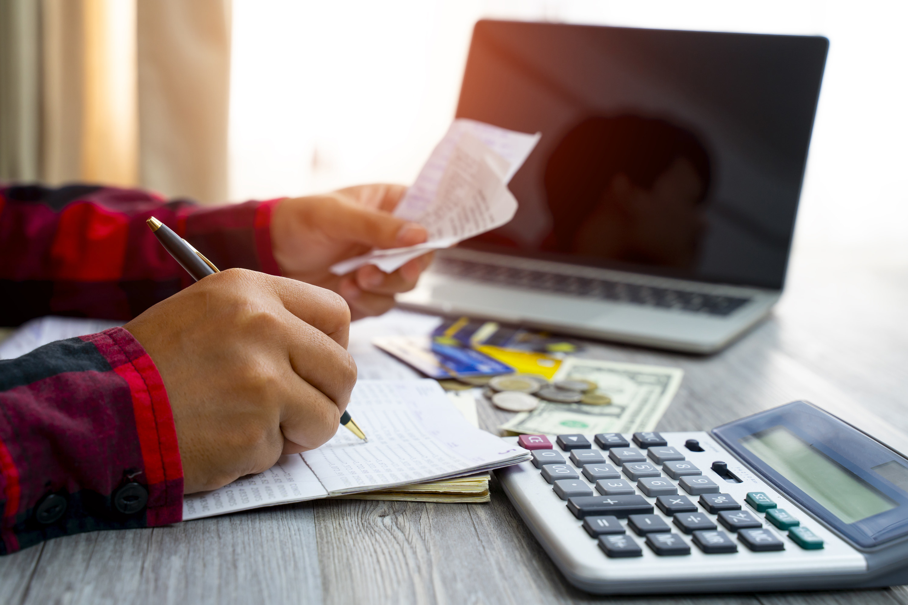 a person paying bills in front of a laptop and calculator