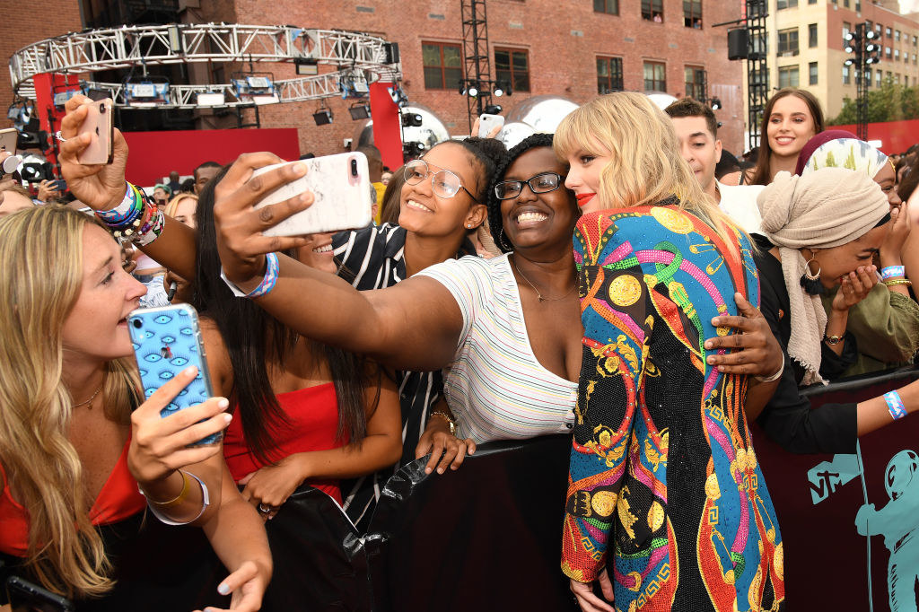 Taylor posing for a selfie with a fan