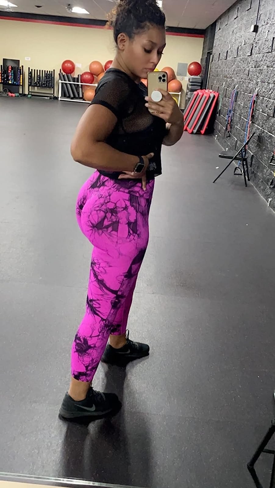 A reviewer wearing black and pink leggings with black top and shoes