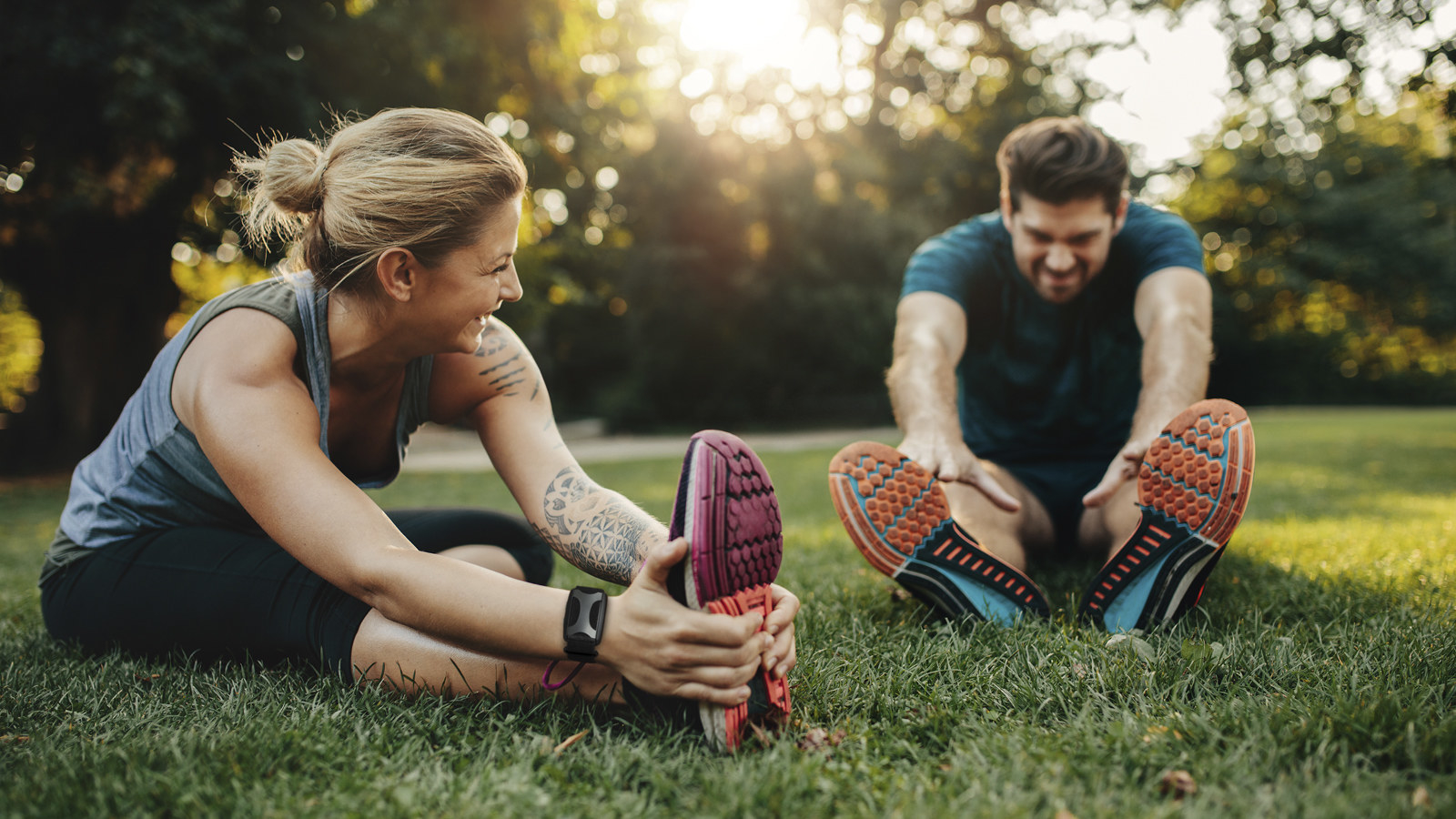 Two people wearing Apollo Neuro stretch after a workout outside
