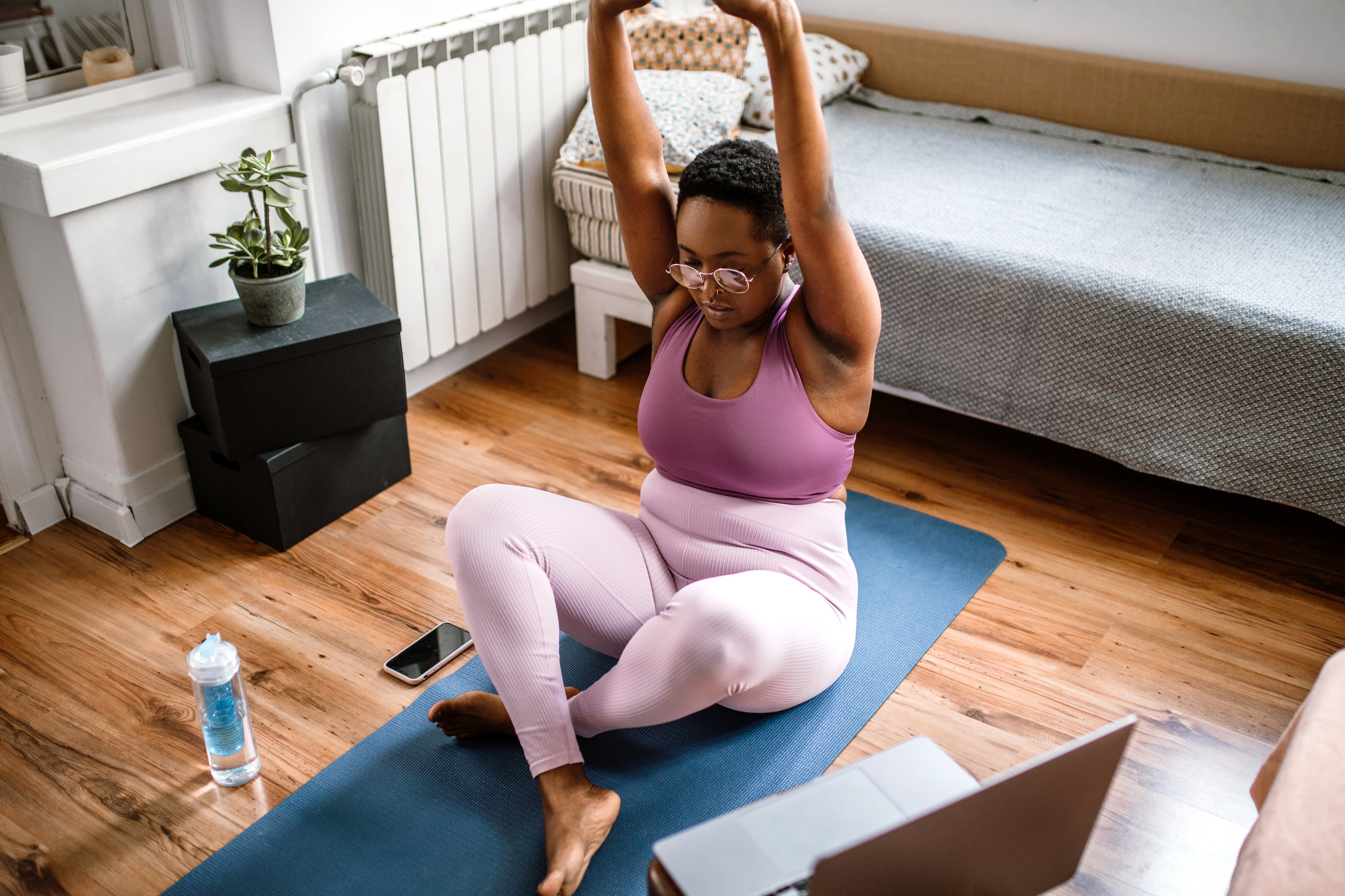 woman doing yoga at home following a class on her laptop