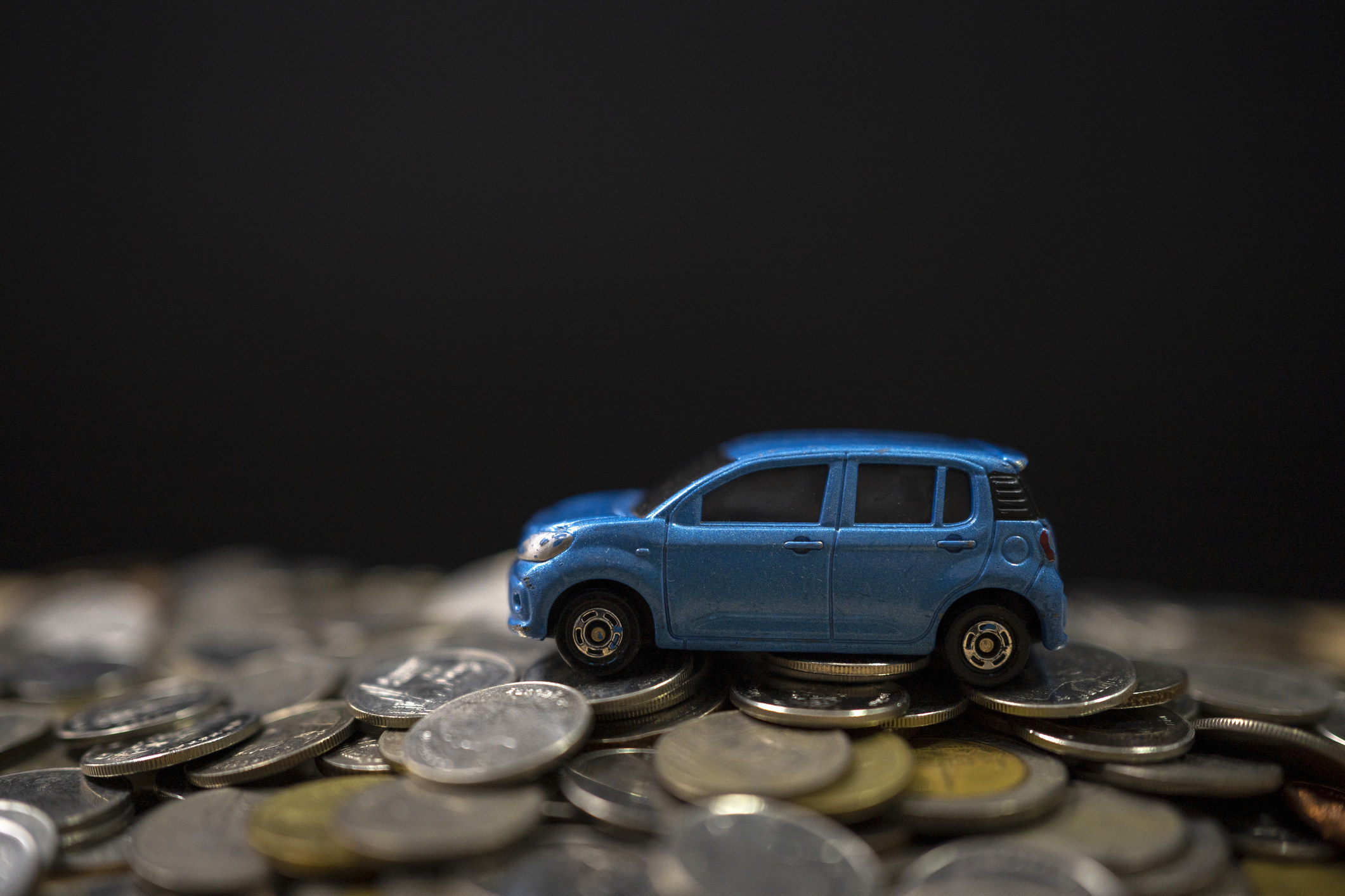 Tiny toy car on top of quarters