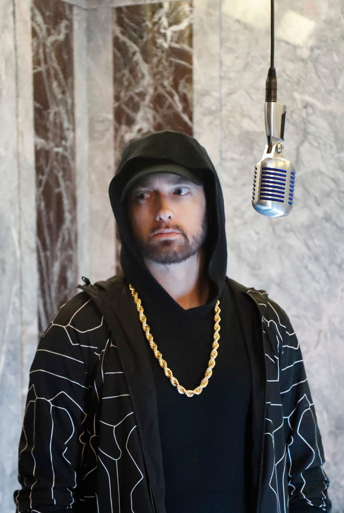 A bearded Eminem standing in front of a hanging mic