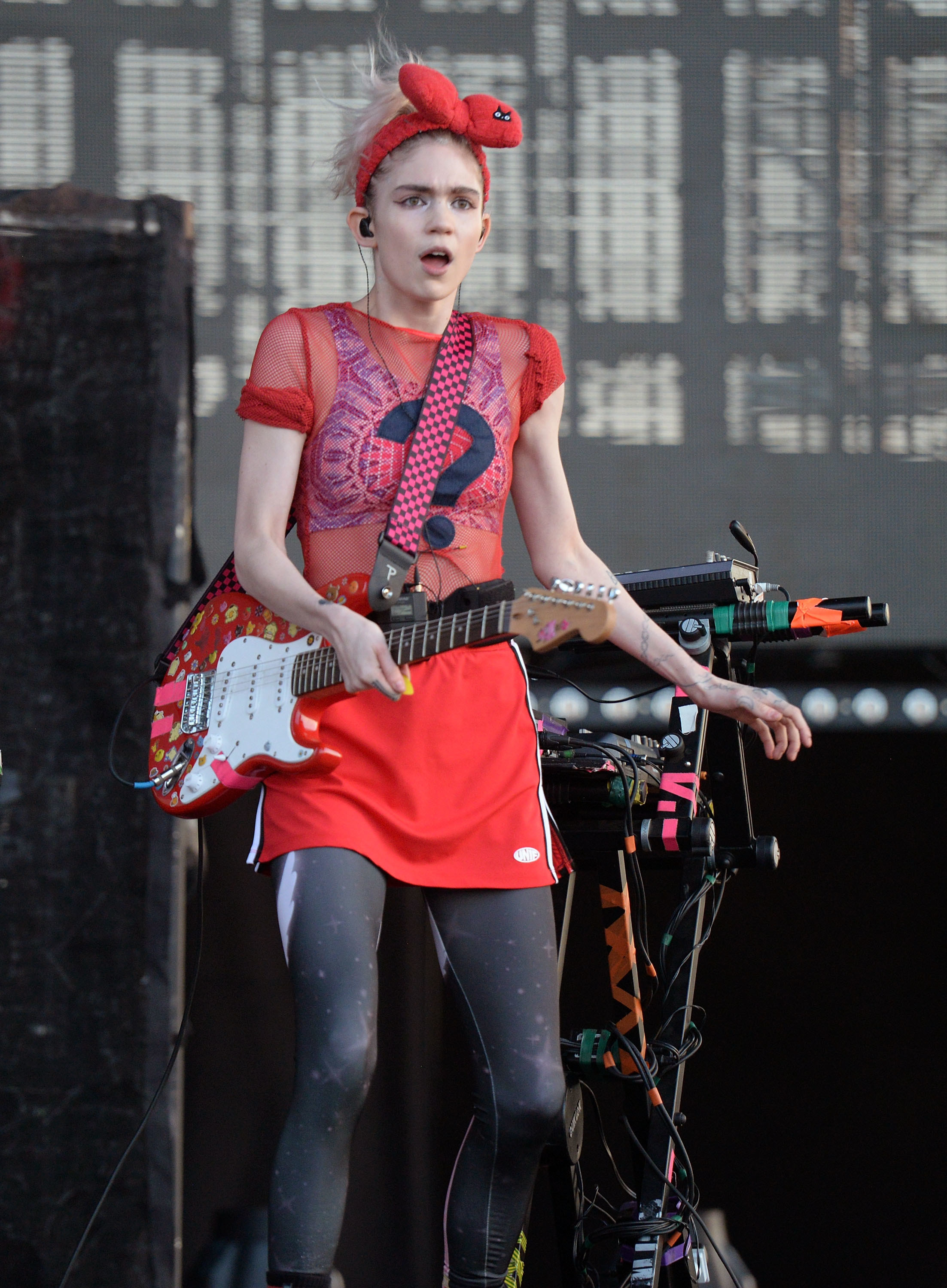 Grimes holding a guitar as she performs onstage