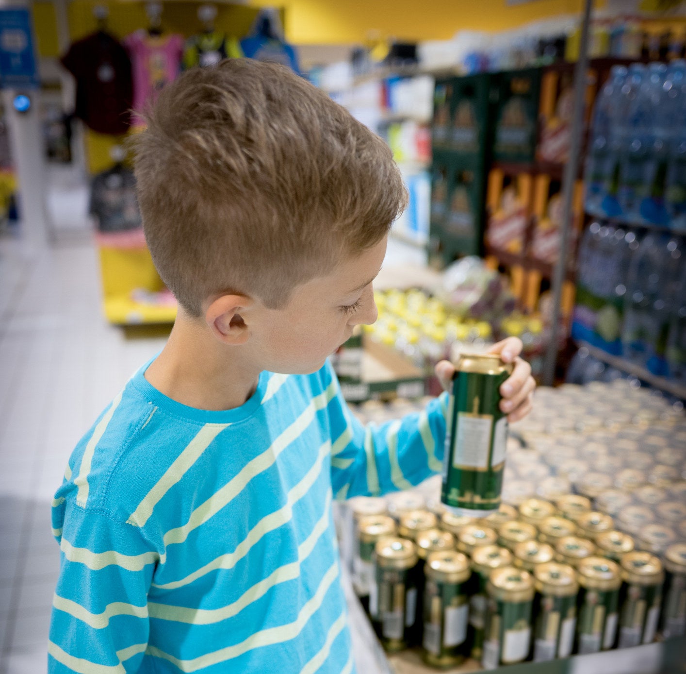 A child holding a beverage can in a store