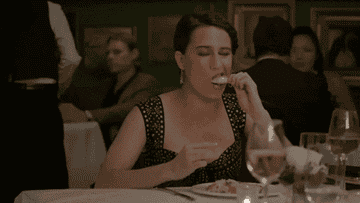 A woman eating a crab leg at a fancy restaurant.