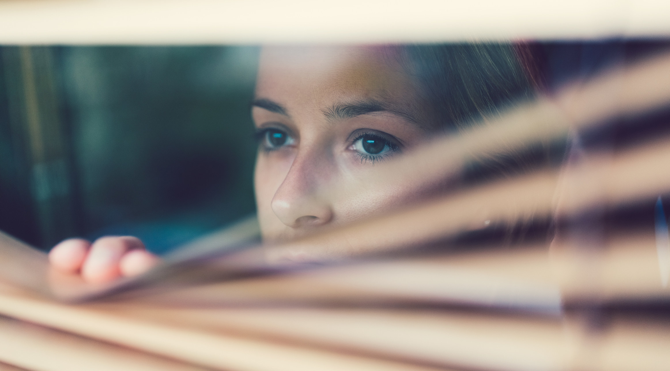 a woman looks worriedly out of their blinds