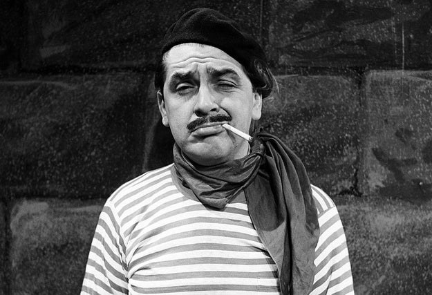 An aggressively French-looking man in a beret and striped shirt smokes a cigarette