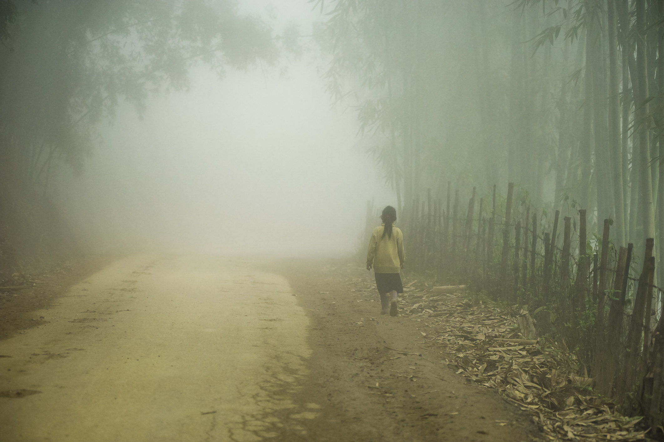 a woman is walking alone on a dirt road