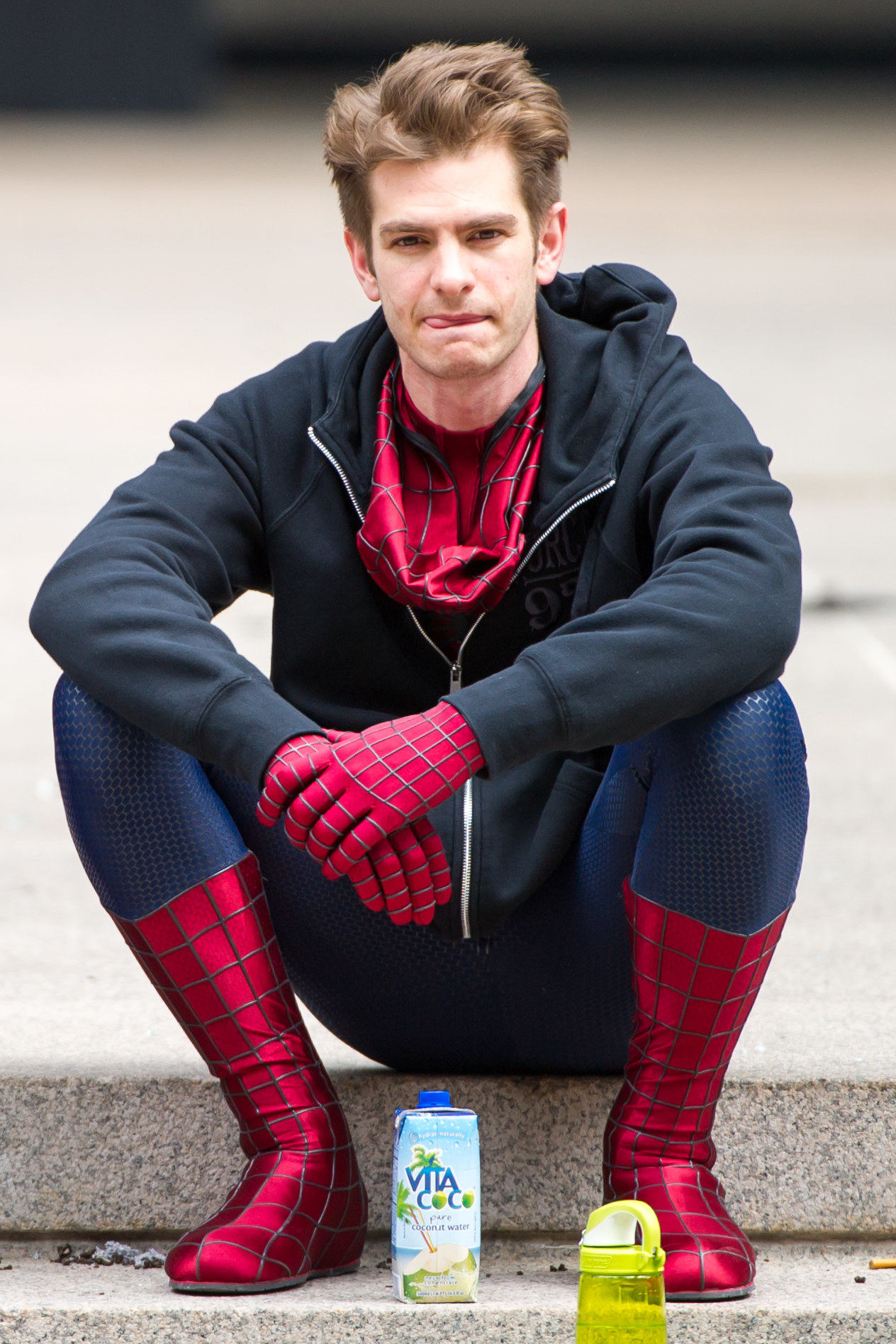 Close-up of Andrew wearing a Spider-Man costume and hoodie and sitting on a step