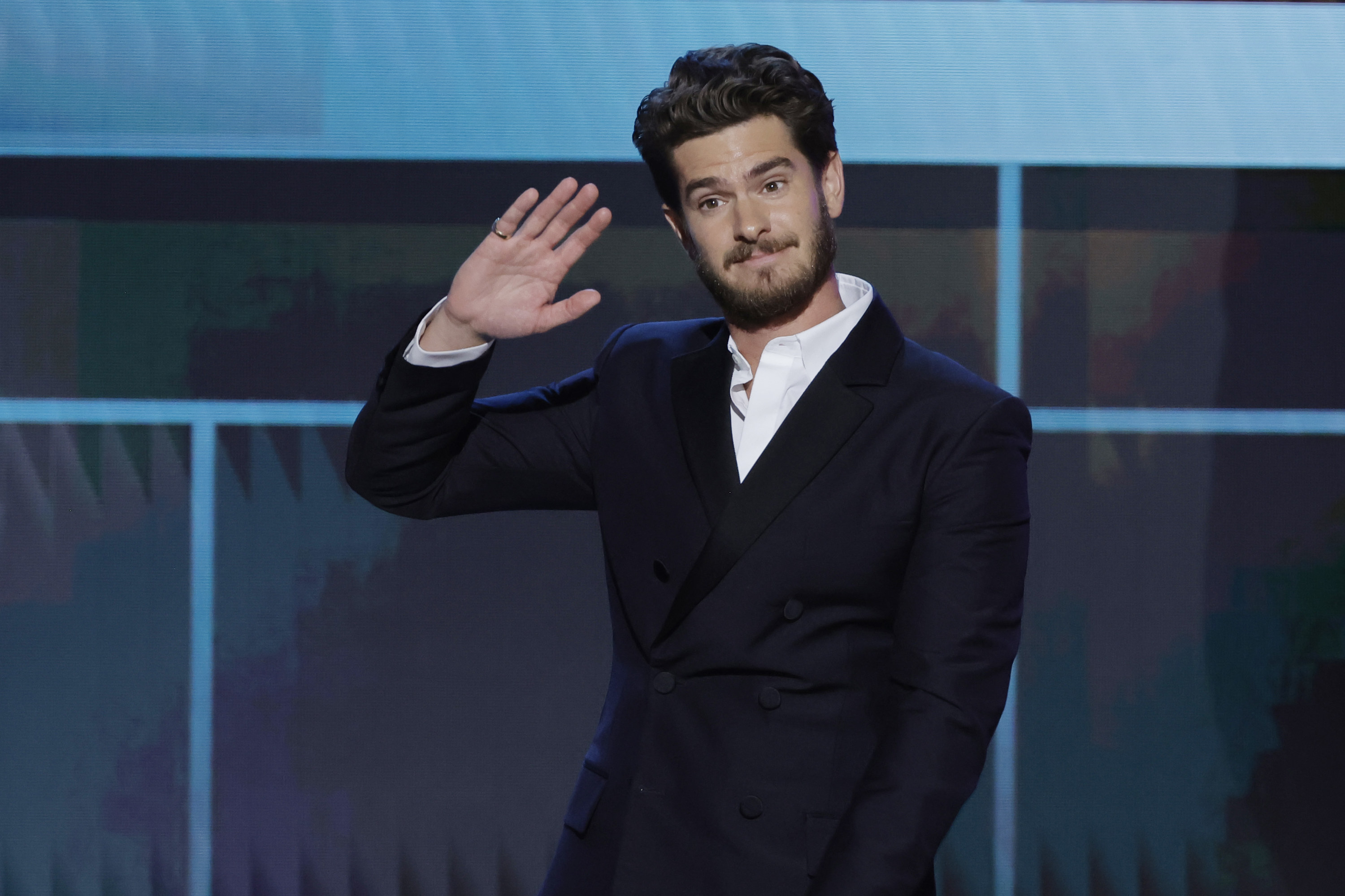 Close-up of Andrew in a suit waving