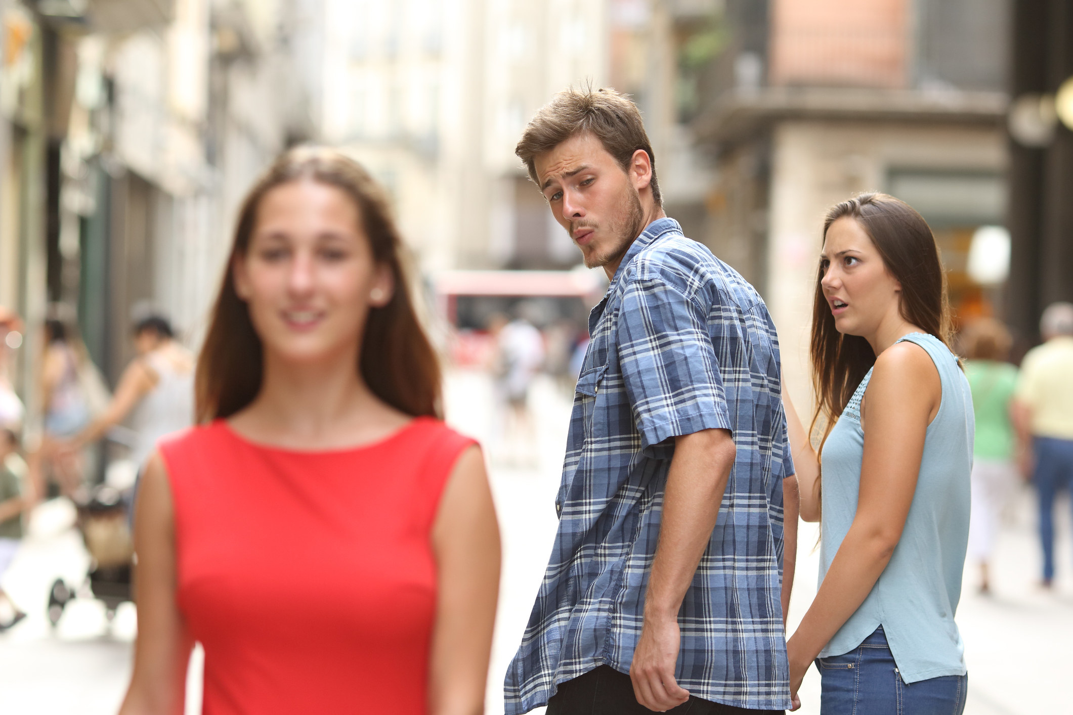 Man looking at another woman while his girlfriend looks on annoyed