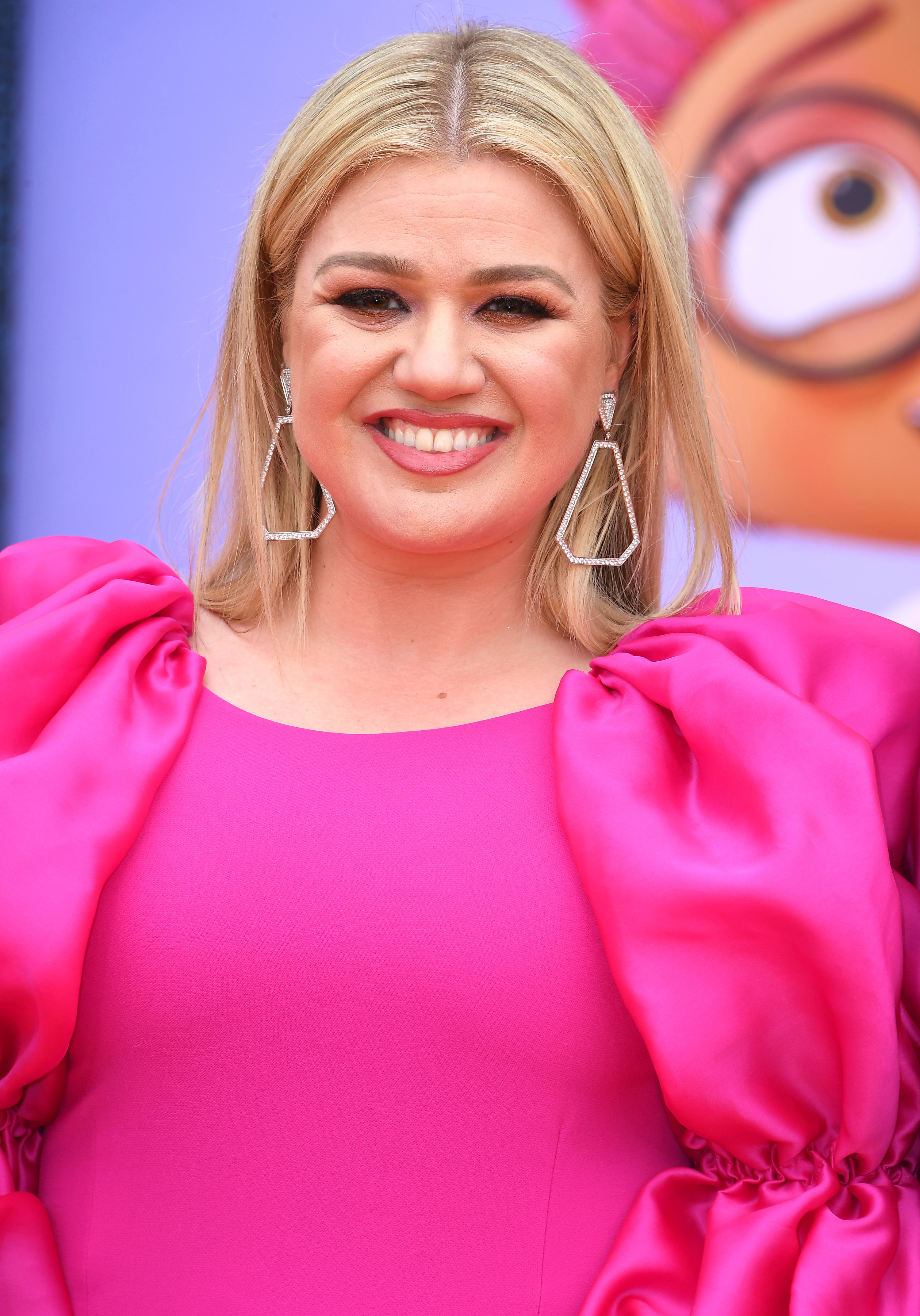 Close-up of Kelly smiling and wearing large, dangly earrings