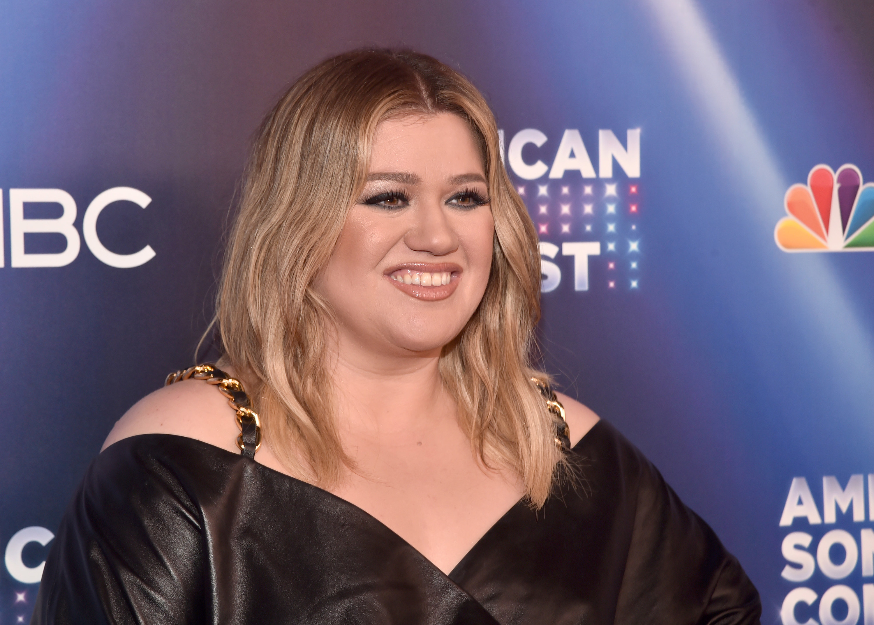 Close-up of Kelly smiling and wearing an off-the-shoulder outfit