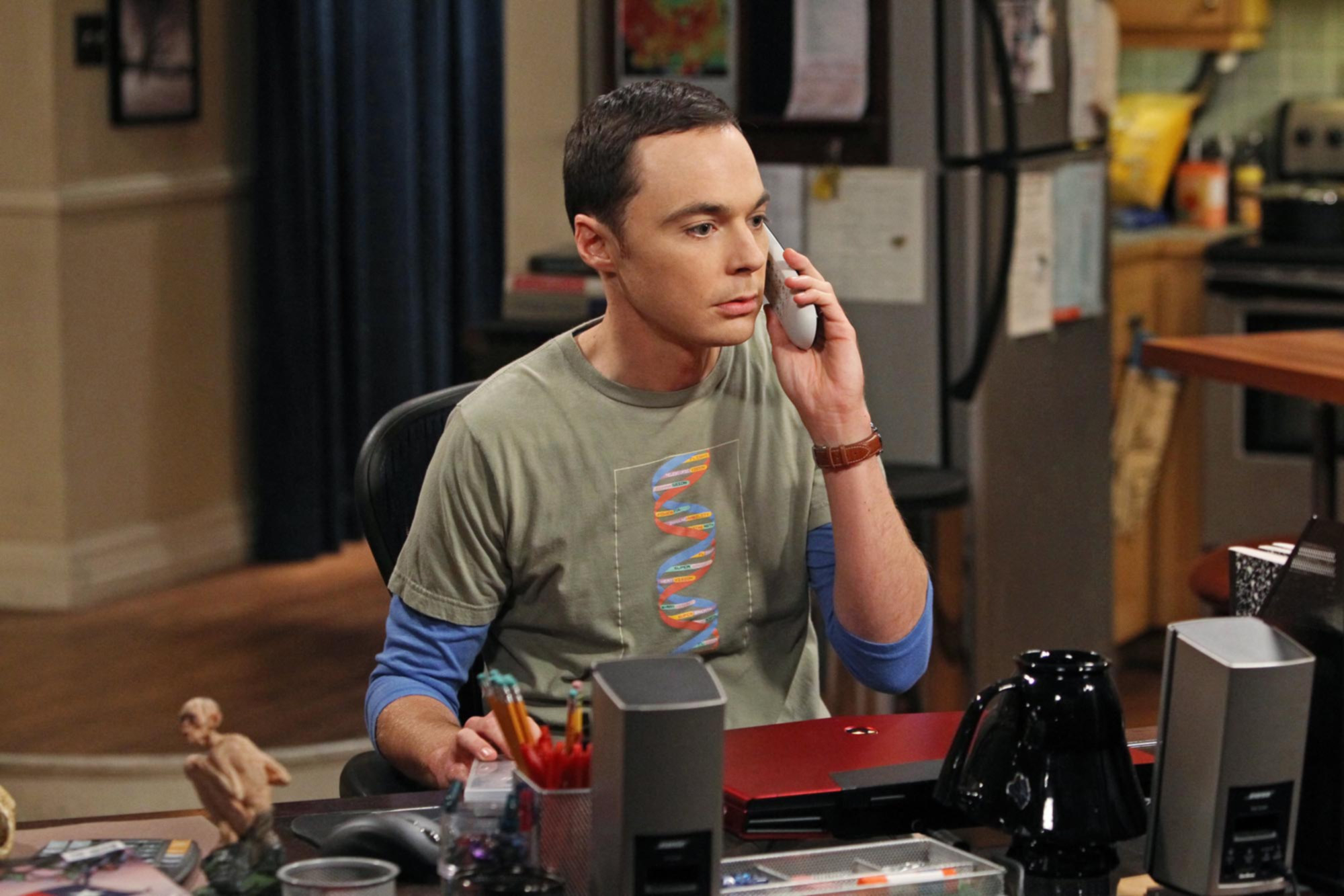 adult sheldon on the phone at his home desk
