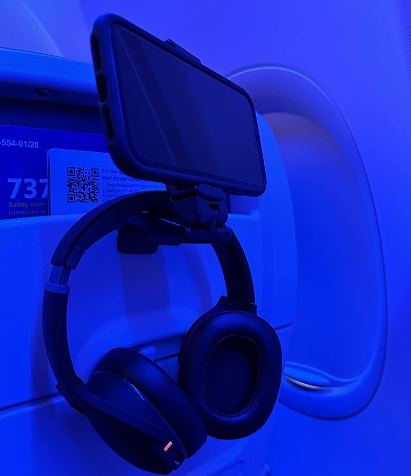 reviewer photo showing their phone mounted to the seat in front of them on an airplane along with their headphones hanging from the mount