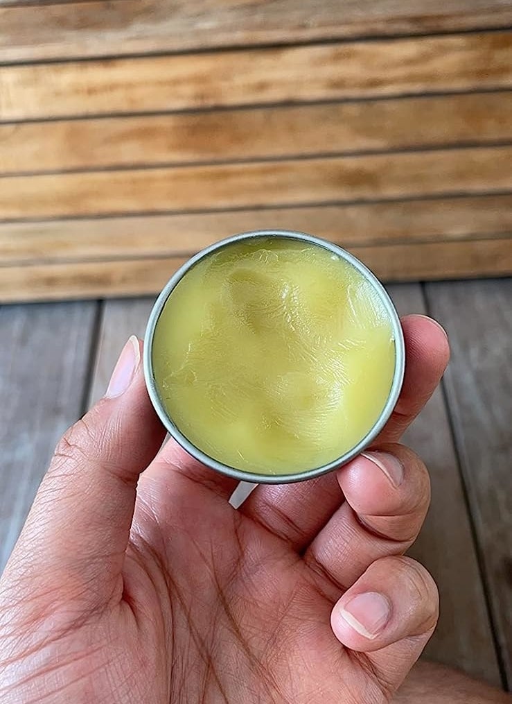 Reviewer holding the open tin of anti bug balm